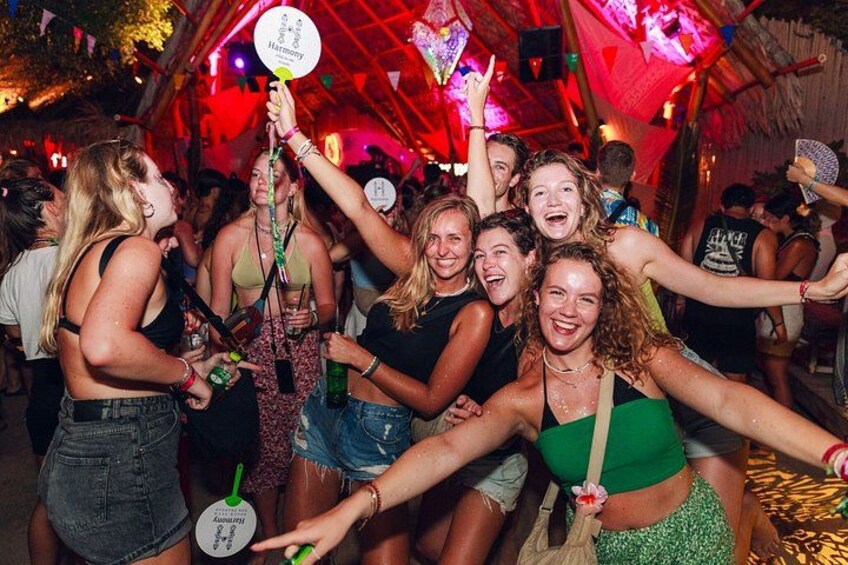A group of people at a party with a tent-like structure and colorful lighting. 1