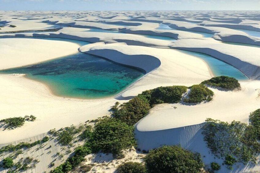 A vast white sand landscape with turquoise waters and green vegetation. 1
