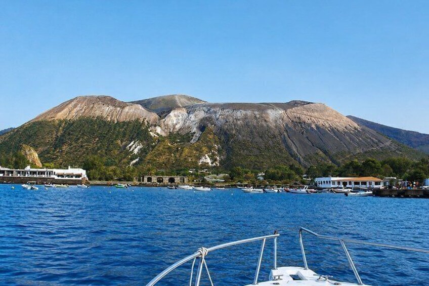 A coastal town with a mountain in the background, boats on the water, and a white building with a red roof. 4