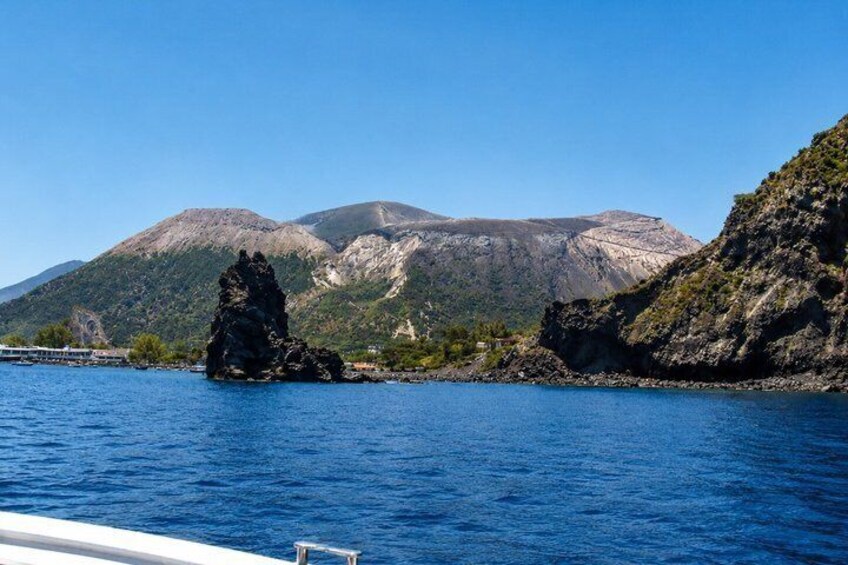 A rocky outcrop in a body of water with mountains in the background. 2