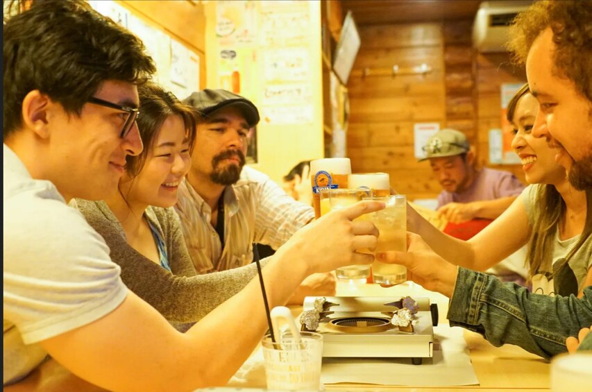 A group of people toasting with beer glasses at a wooden table in a rustic setting. 1