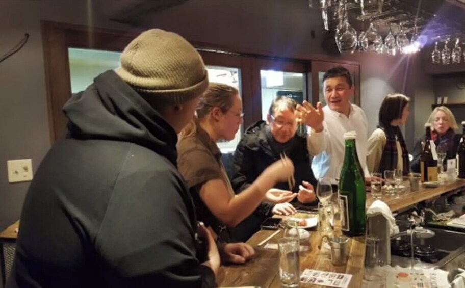 A group of people at a bar with bottles and glasses. 2