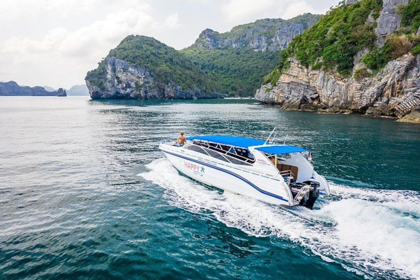 A speedboat on a calm sea with rocky cliffs in the background. 2