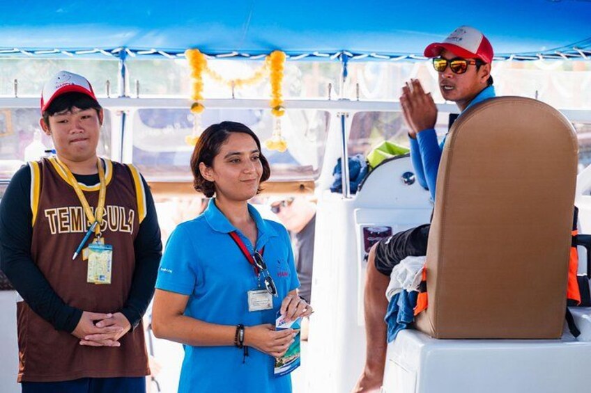 Three people on a boat, one wearing a 'Temisula' shirt, another in a blue shirt, and the third in a red cap. 4