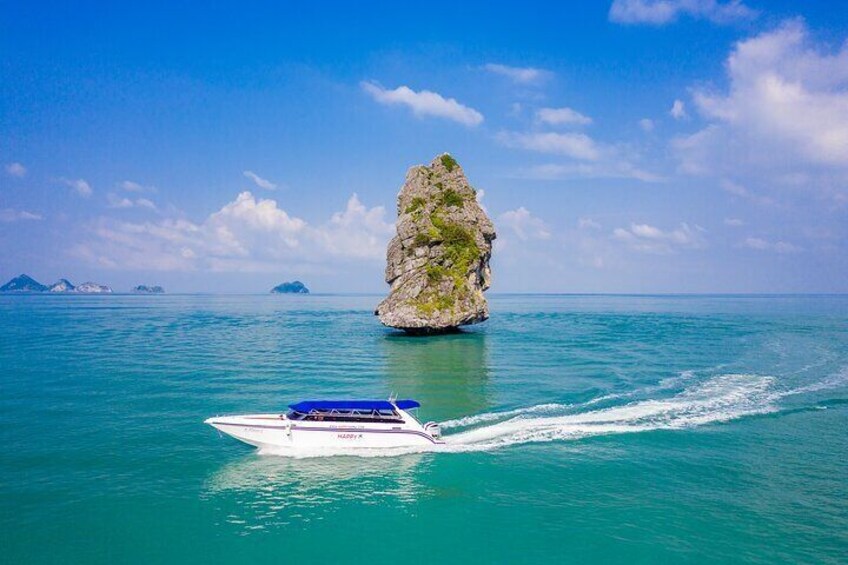 A boat on turquoise water with a large rock formation in the background. 3