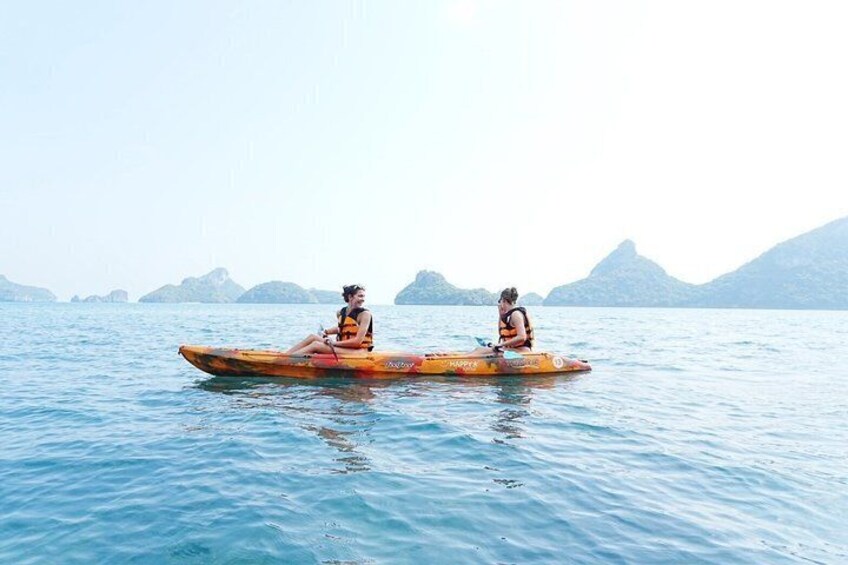 Two people kayaking on a calm body of water with mountains in the background. 1