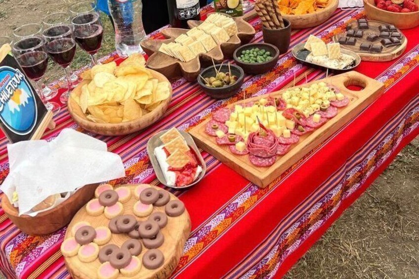 A picnic spread with various foods and drinks on a red cloth. 5
