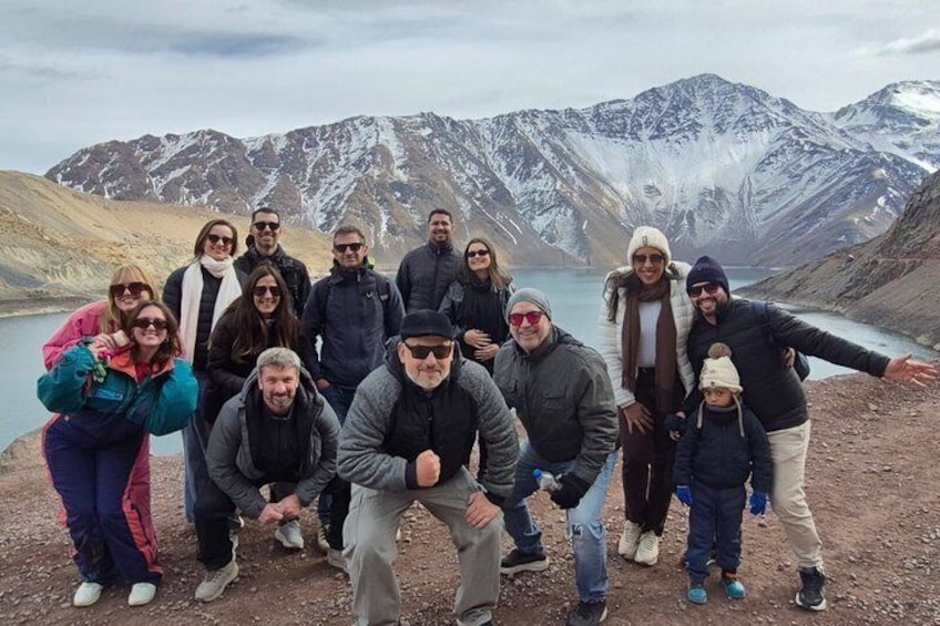 A group of people posing in front of a mountainous landscape with a lake. 4