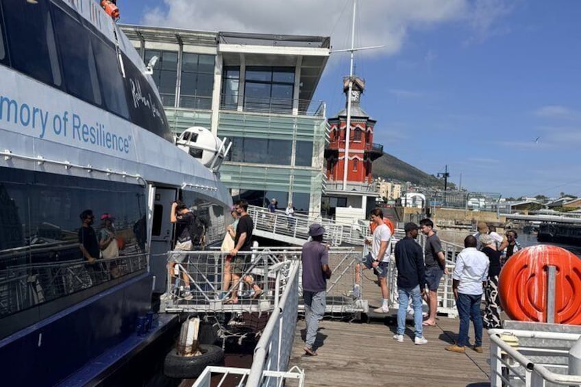 A ferry named 'Memory of Resilience' docked at a pier with people boarding and disembarking. 3