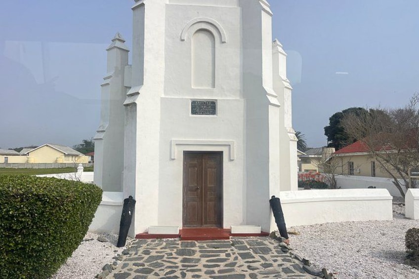 A white church with a wooden door and a stone-paved entrance. 2