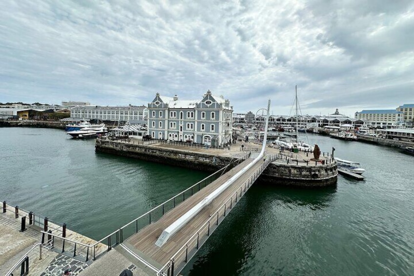 A waterfront promenade with a bridge, historic buildings, and a marina. 1