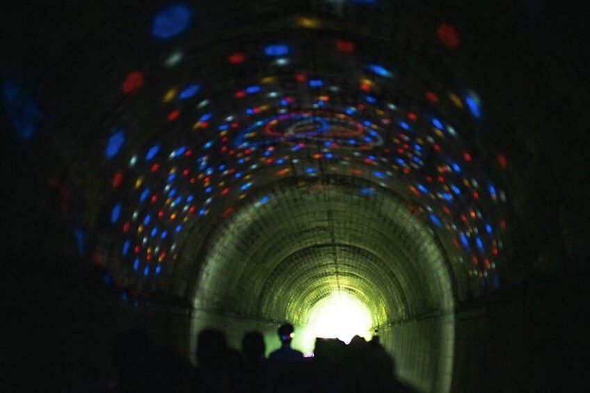 A tunnel with colorful lights and a central light source. 5