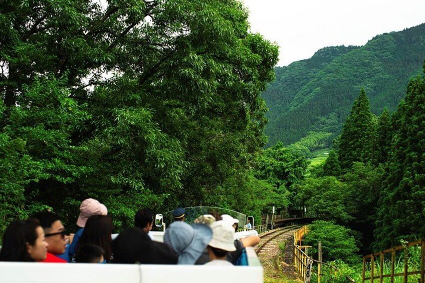 A train on tracks surrounded by lush greenery and hills. 4