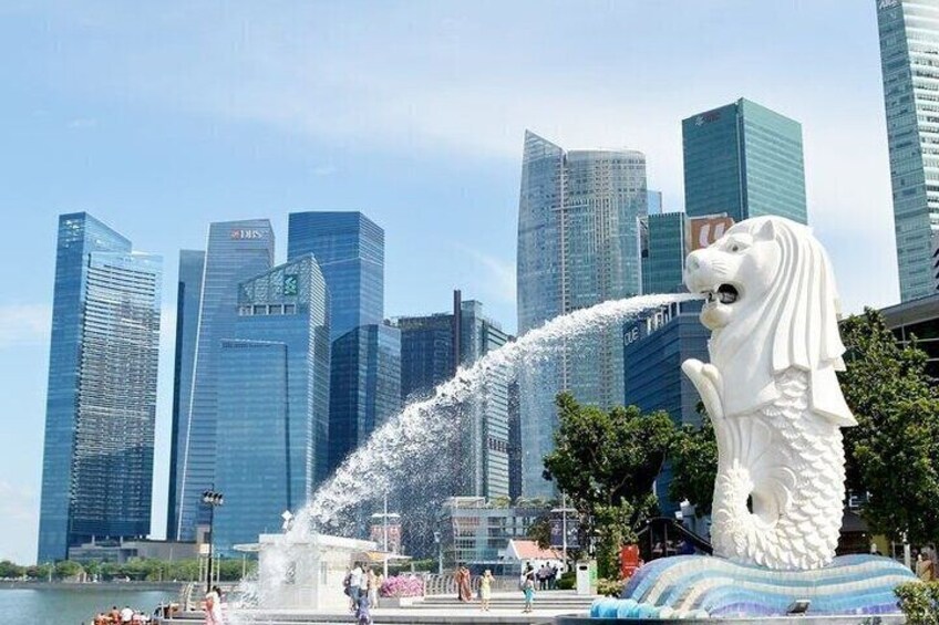 A water fountain with a lion statue in front of modern skyscrapers. 2