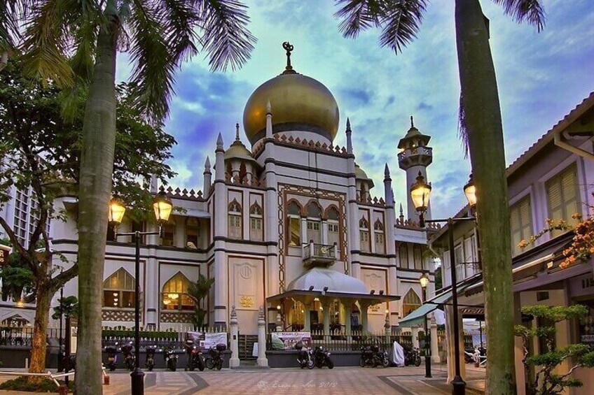 A mosque with a large golden dome, surrounded by palm trees and street lamps. 4