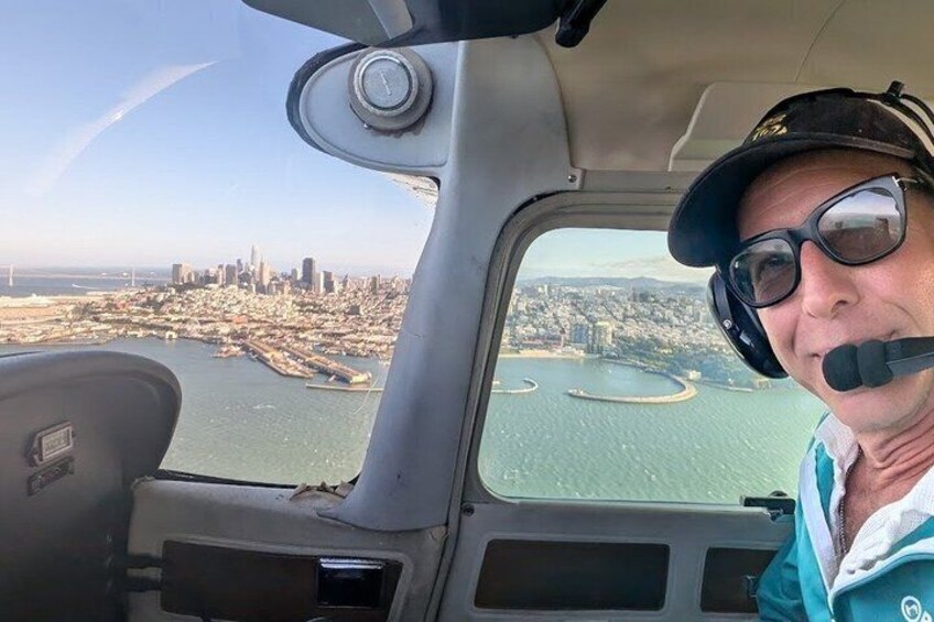 A view from an aircraft cockpit with a cityscape and water body below. 3
