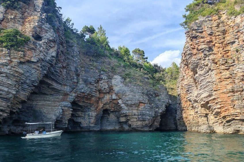 A boat on a calm sea, rocky cliffs, and sparse vegetation. 3
