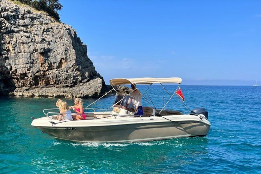 A small motorboat with two people and a child on board, near a rocky coastline. 2