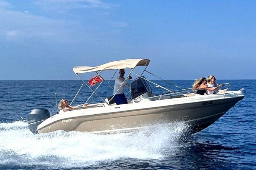 A speedboat with a canopy, a red flag, and three people on board. 2
