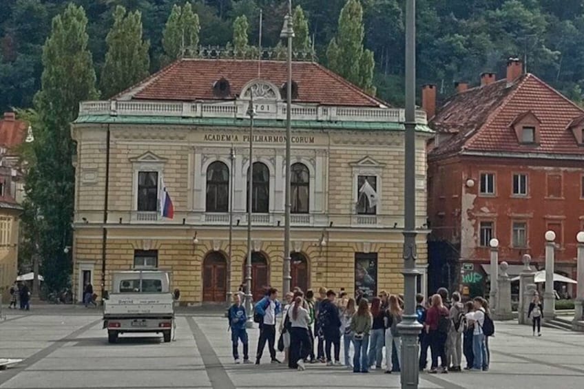 A historic building with a green roof and a flag, a crowd of people in front, and a truck parked nearby. 4