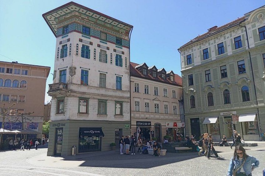 A public square with historic buildings, a café, and people walking. 2