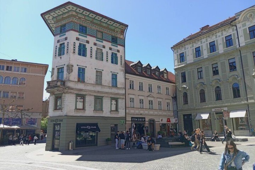 A public square with historic buildings, a café, and people walking. 2