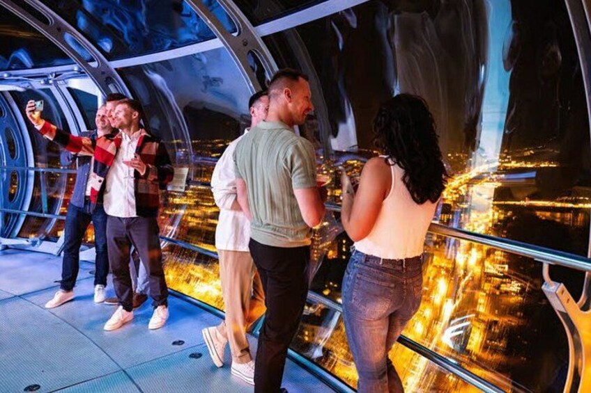 People taking a selfie in a futuristic glass structure with a cityscape view. 3