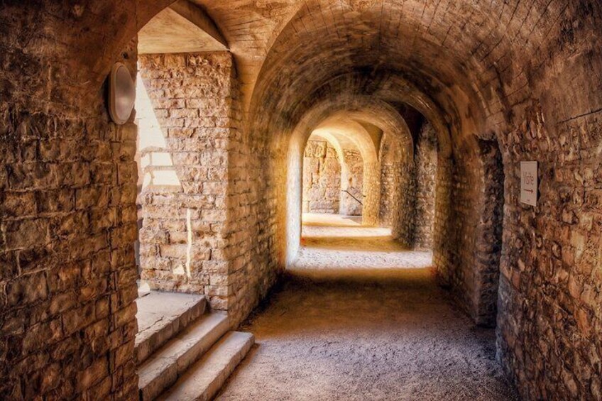An arched stone corridor with steps leading to a brighter area. 4