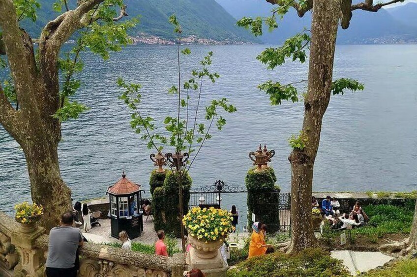 A lakeside park with trees, a gazebo, and people walking and sitting. 3