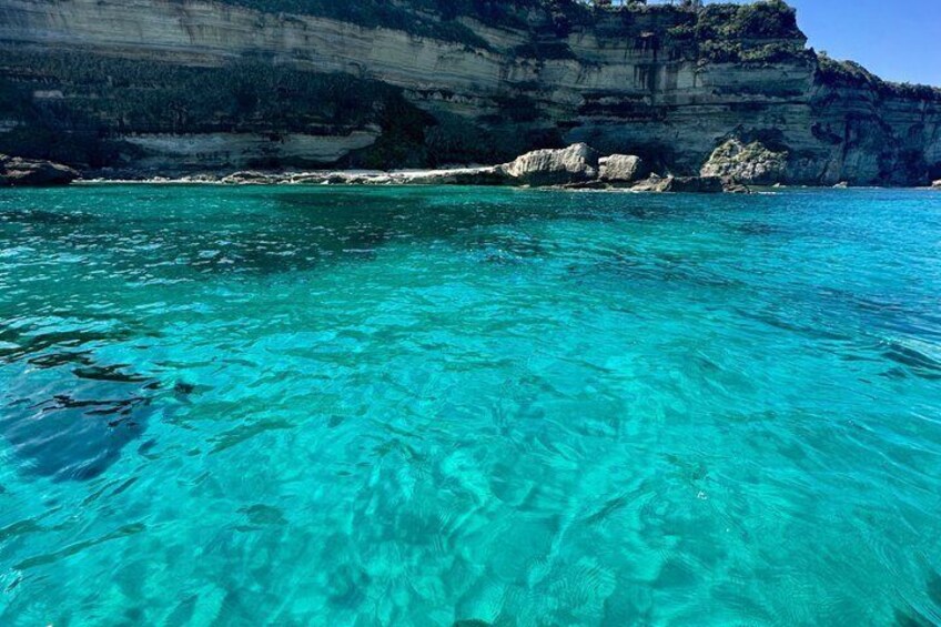 Clear turquoise water, rocky cliffs, and a clear sky. 4