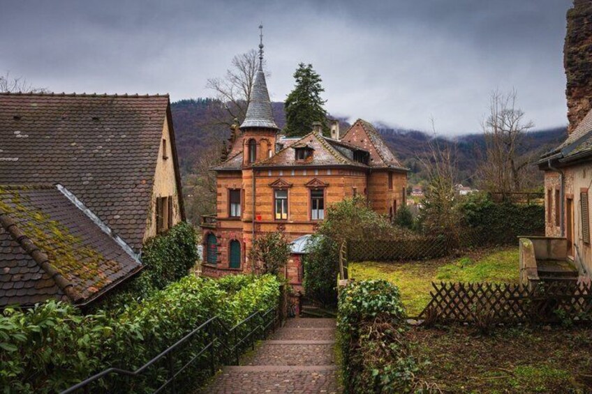 A red brick building with a tower, surrounded by greenery and a stone wall. 3
