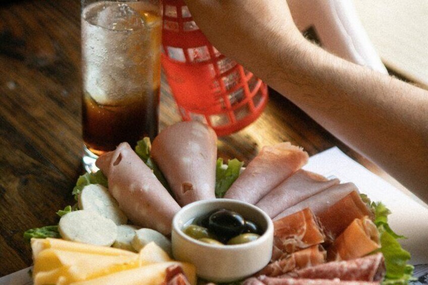 A charcuterie board with various meats, cheese, and olives on a wooden table. 3
