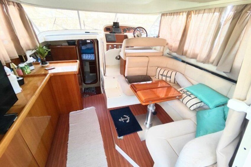 Un interior acogedor de autocaravana con una mesa de madera, asientos con cojines y un panel de control. 4