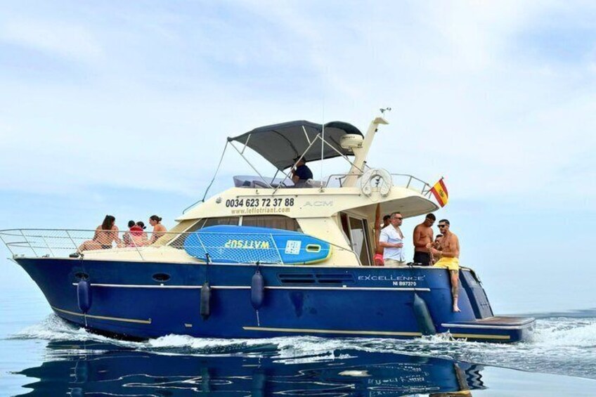 A blue boat with people on board, a flag, and a website address. 2