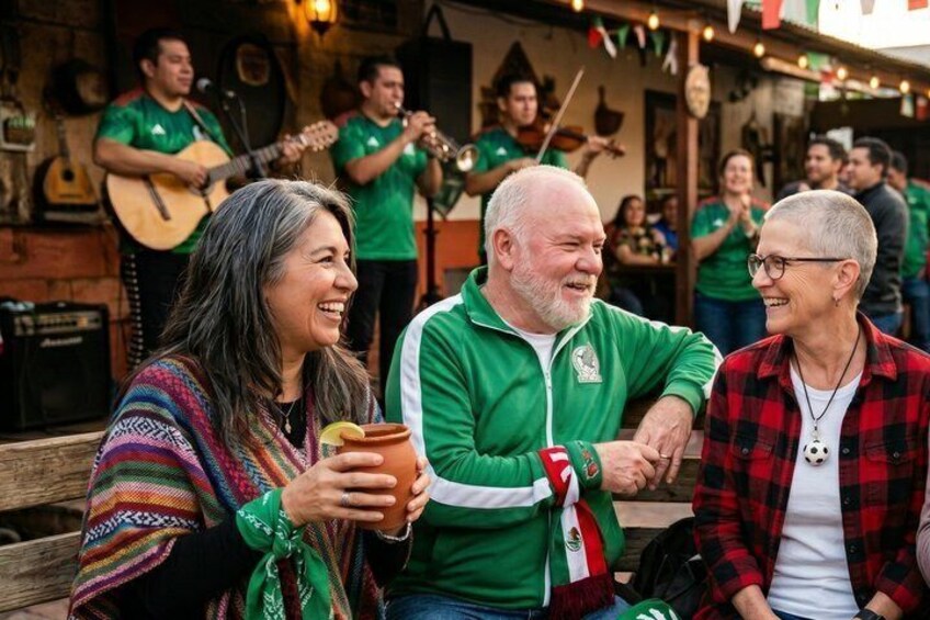 A group of people in a casual outdoor setting, possibly a festival or gathering, with a musician in the background. 1