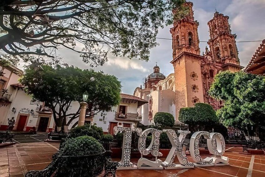 A plaza with a church, trees, and a large 'Toxco' sign. 1