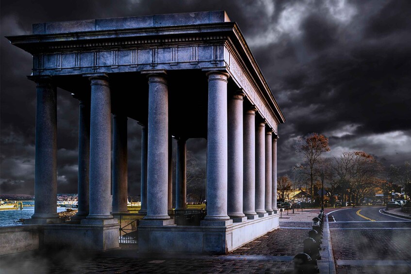 A neoclassical building with columns, a paved walkway, and a curved road in the background. 1