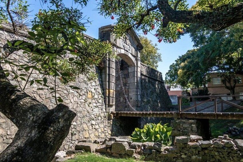 A stone bridge, a stone wall, and a tree. 4
