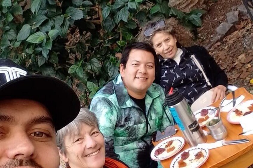 A group of people sitting at an outdoor table with food and drinks. 5