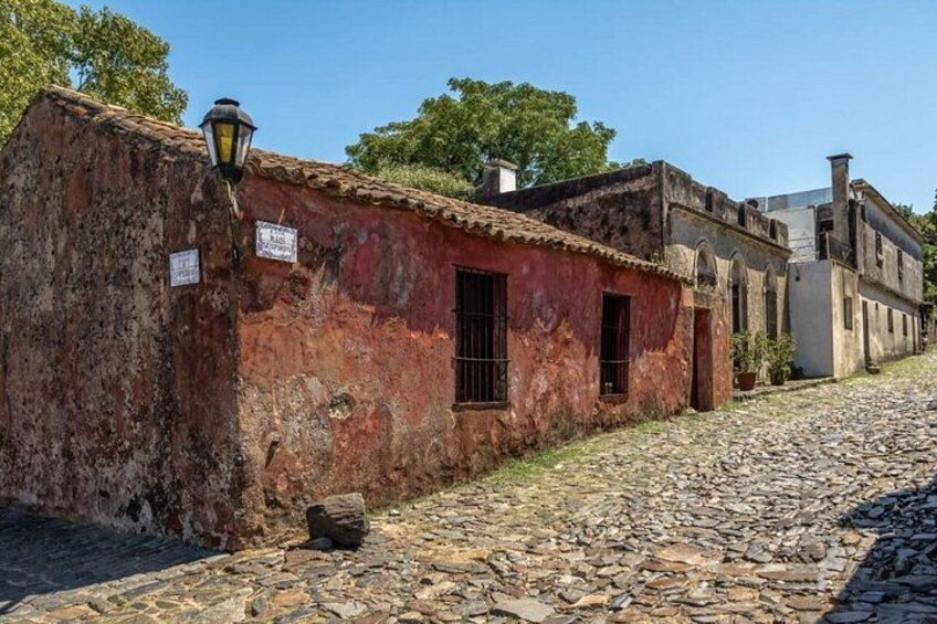 A cobblestone street with old buildings, a lamp post, and a sign. 3