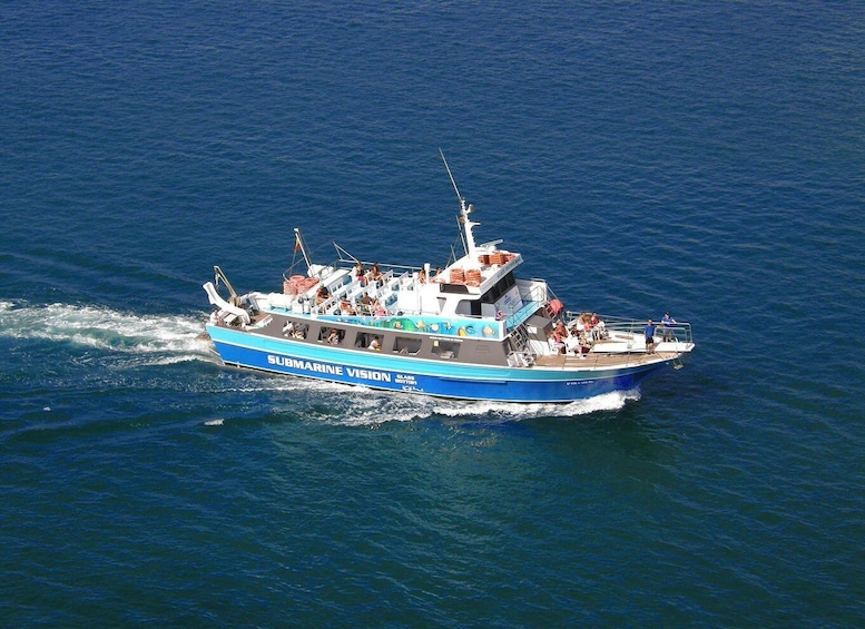 A blue boat named 'Submarine Vision' with passengers and a wake behind it. 5