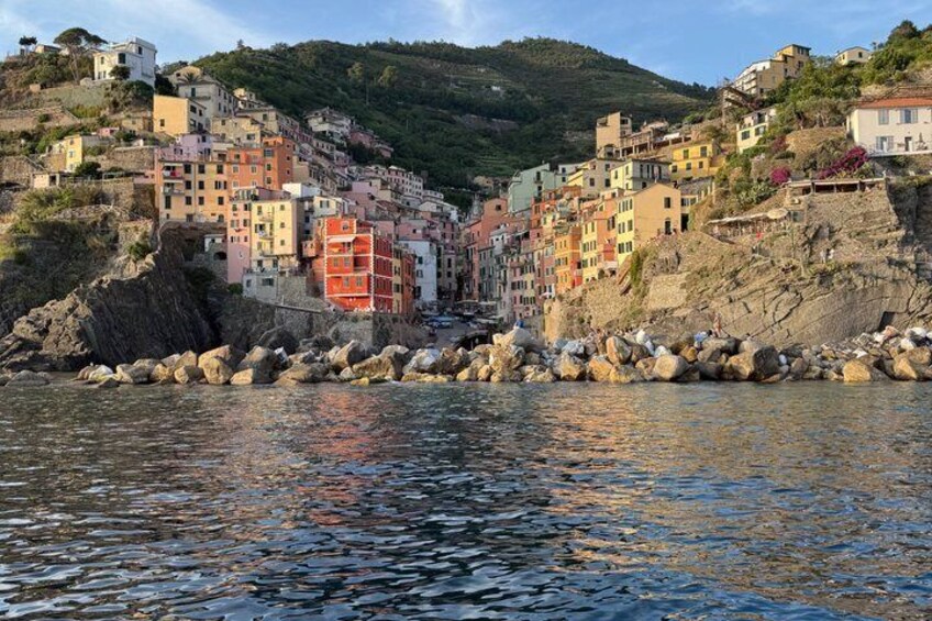 A coastal town with colorful buildings, rocky shoreline, and a hill in the background. 5
