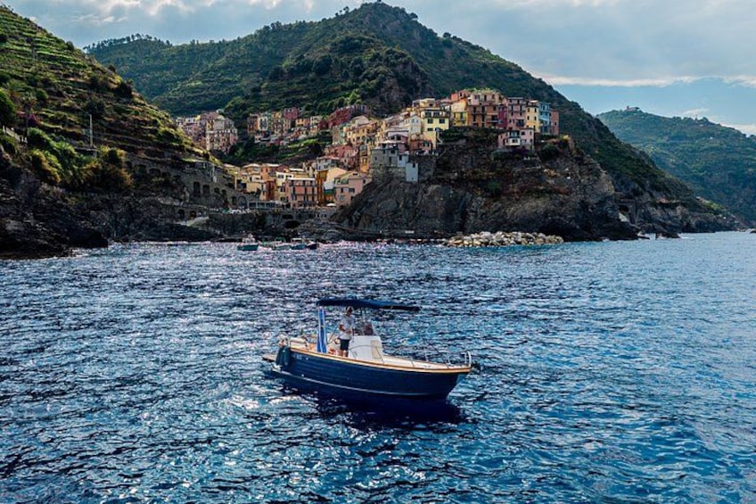 A boat on calm water with colorful buildings on a hillside in the background. 5