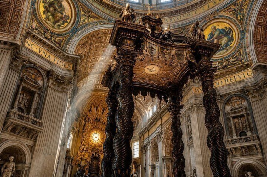 An ornate architectural interior with intricate carvings and a central chandelier. 2