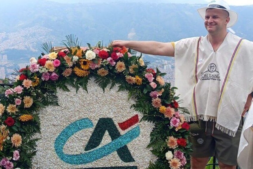 A person standing next to a floral arrangement with a logo on a wall. 3
