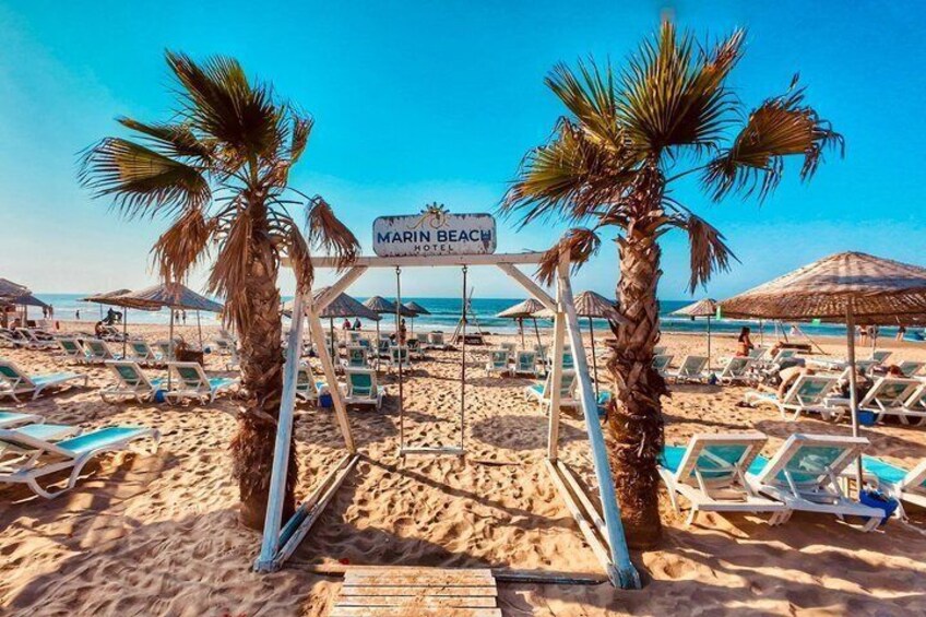 A beach with lounge chairs, palm trees, and a sign for Marin Beach Hotel. 3