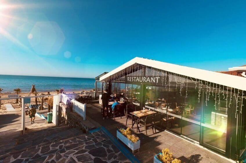 A beachfront restaurant with outdoor seating and a view of the ocean. 4
