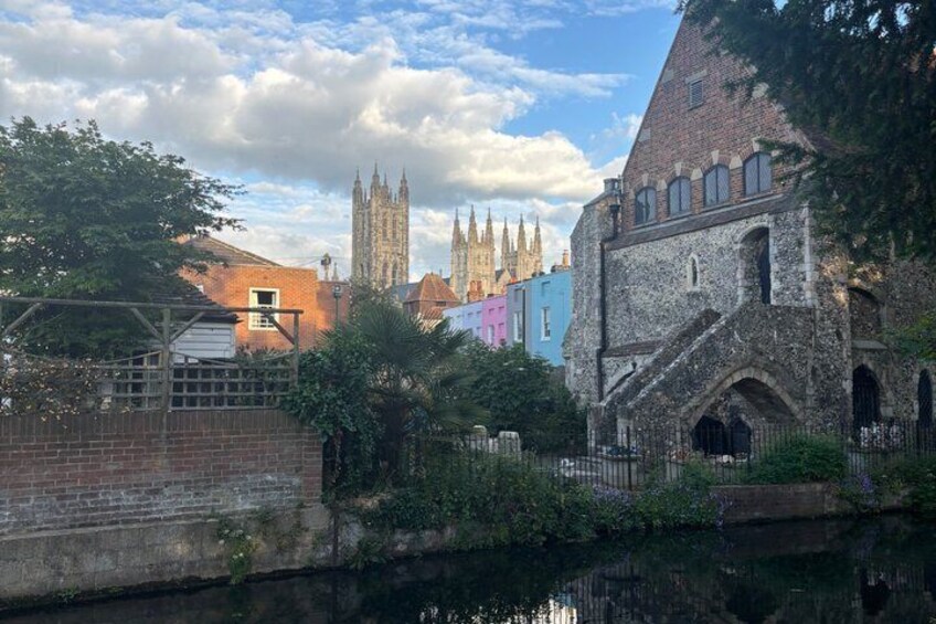 A historic building with a stone facade, a canal, and colorful buildings in the background. 3