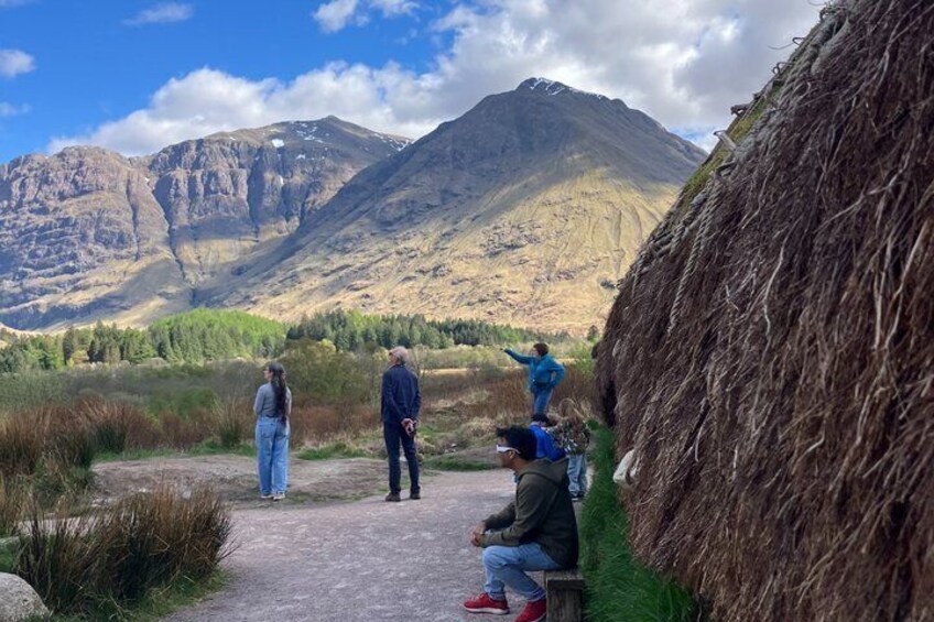 A group of people standing and sitting by a path with mountains in the background. 5