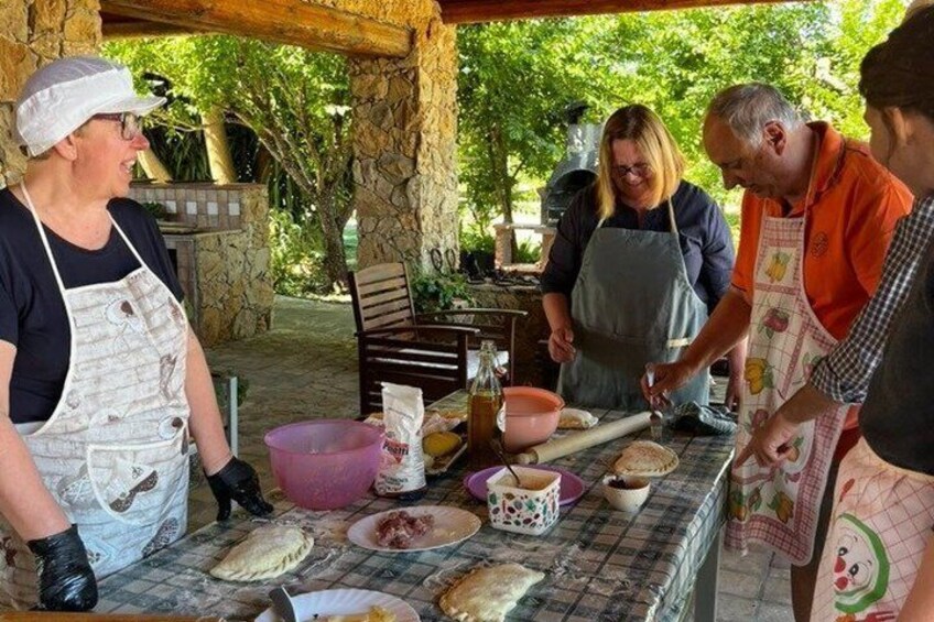 People preparing food outdoors with a table, bowls, and cooking utensils. 3